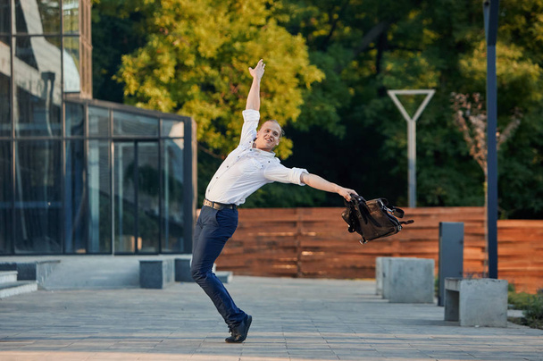 Божевільний молодий бізнесмен танцює на вулиці з сумкою. Святкування перемоги. Гнучкість і грація в бізнесі
 - Фото, зображення