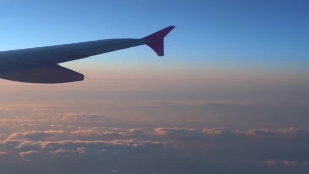 In de lucht, uitzicht op vliegtuig vleugel silhouet met donker blauwe hemel horizon en wolk achtergrond in zon opkomst tijd, bekeken vanuit vliegtuig venster - Video
