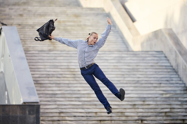 Crazy young businessman dancing on the street with bag. Celebrating victory. Flexibility and grace in business - Foto, Imagem