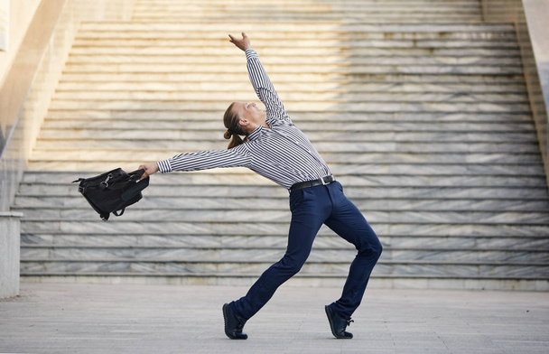 Giovane uomo d'affari pazzo che balla per strada con la borsa. Festeggiamo la vittoria. Flessibilità e grazia nelle imprese
 - Foto, immagini
