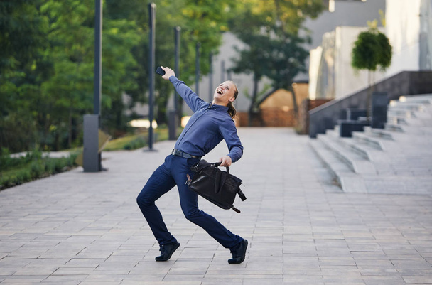 Joven empresario loco bailando en la calle con bolsa. Celebrando la victoria. Flexibilidad y gracia en los negocios
 - Foto, Imagen