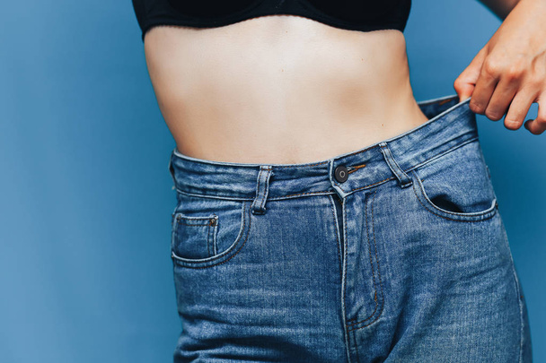 corpo magro da mulher com calças soltas jeans, corpo leve com roupas soltas, conceito de baixo teor de gordura corporal esbelto e saudável
 - Foto, Imagem