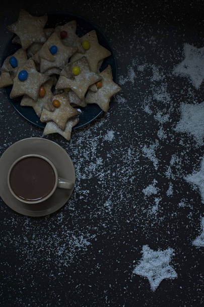 Kookos tähden muotoinen joulun evästeet koristeltu kookos pelimerkkejä tummalla pohjalla
 - Valokuva, kuva