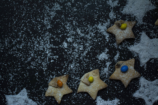 Χριστουγεννιάτικα μπισκότα σε σχήμα αστεριού καρύδας διακοσμημένα με μάρκες καρύδας σε σκούρο φόντο - Φωτογραφία, εικόνα