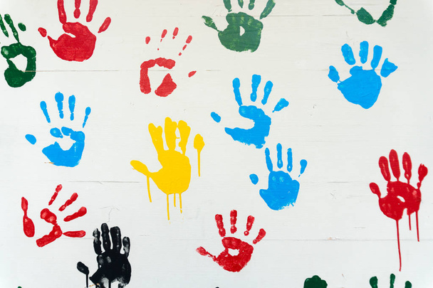 разноцветные отпечатки рук на белой стене
 - Фото, изображение
