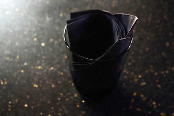 Czarne tkanki w czarnym szkle na ciemnym stole kawiarni ze złotym pyłem powierzchni - Zdjęcie, obraz