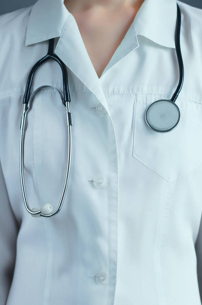 Kaukasische meisje in medische witte kleren met een stethoscoop close-up. - Foto, afbeelding