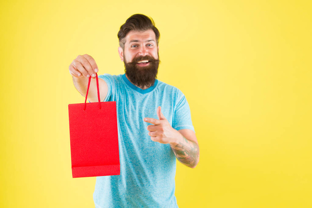 Man with purchase. Impulse purchase. Purchase concept. Male motives for shopping appear to be more utilitarian. Aspects can influence customer decision making behavior. Hipster hold shopping bag - Photo, image