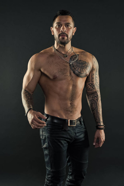 Tattoo culture concept. Tattoo brutal attribute. Man brutal unshaven hispanic appearance tattooed arms. Bearded man show tattooed torso. Brutal strict macho with tattoos. Masculinity and brutality - Photo, image