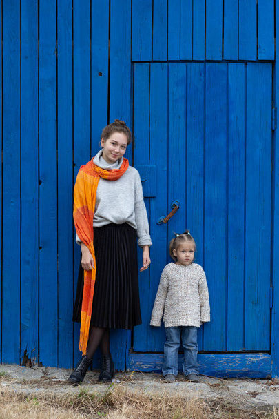 Young woman and child on blue wooden background looking at camera - Foto, Imagem