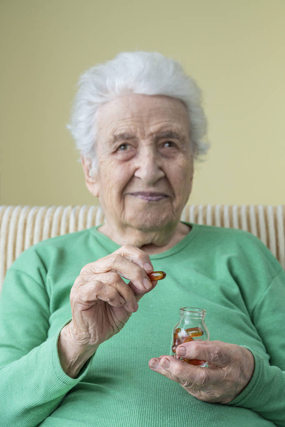 uma mulher sênior encantadora segurando cápsulas de vitamina
 - Foto, Imagem