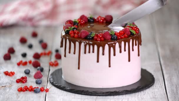 Beautiful homemade cake with summer berries, chocolate frosting on white table - Footage, Video