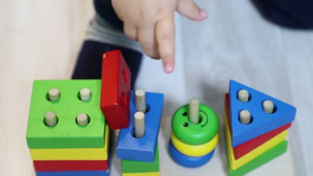 One year old child (boy) plays with geometric sorter (wooden constructor), close-up of child's hand and toy, 50 fps, slow motion - Video, Çekim
