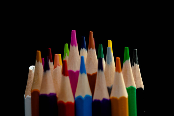 Lápices de madera en todos los colores vistos desde la hoja de lápices. Lápices de colores apilados con un fondo negro. Colores. Regreso a la escuela, educación
. - Foto, imagen