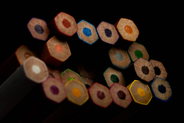 Wooden pencils in all colors seen at the base of pencils. Colored pencils stacked. With a black background.Colors. Back to school, education. - Photo, Image