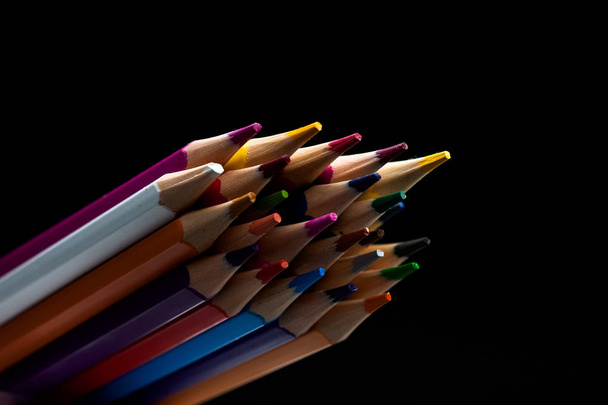 Wooden pencils in all colors seen from the sheet of pencils. Colored pencils stacked with a black background. Colors. Back to school, education. - Photo, Image