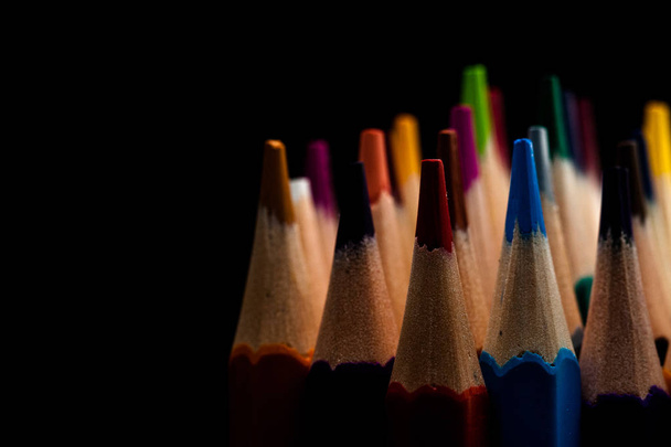 Ξύλινα μολύβια σε όλα τα χρώματα που φαίνονται από το φύλλο των μολυβιών. Χρωματιστά μολύβια στοιβάζονται με μαύρο φόντο. Χρώματα. Επιστροφή στο σχολείο, εκπαίδευση. - Φωτογραφία, εικόνα