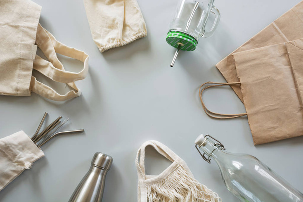 Eco natural metallic straws, cotton bag, glass and metal bottle on grey. Sustainable lifestyle concept. Zero waste, plastic free. Pollution environment. - 写真・画像