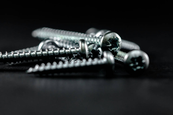 Steel screws grouped on a black background. Tools for DIY. - Фото, изображение
