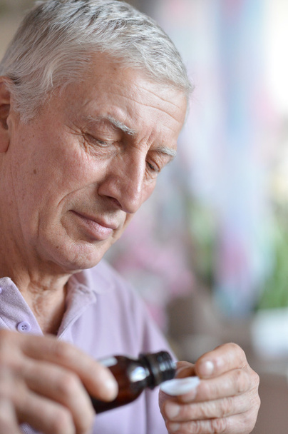 Older man taking a medicine - Foto, afbeelding