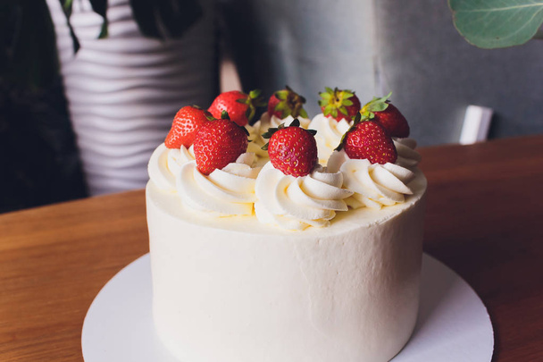 Sweet cake with strawberries on plate on wooden background. - Valokuva, kuva