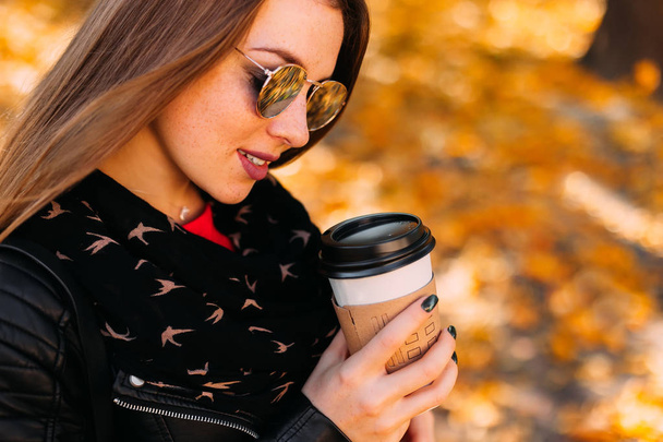  girl in leather jacket and sunglasses holding paper cup. Casual - Photo, Image