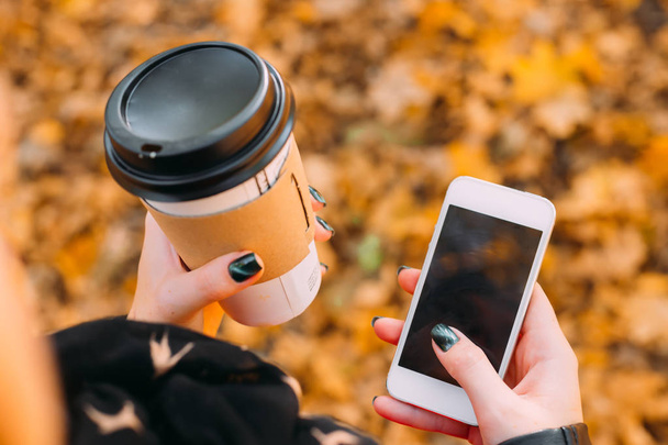 Detailní záběr papírového kelímku s kávou a mobilním telefonem v ruce - Fotografie, Obrázek