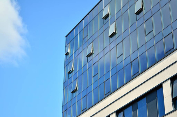 Nuevo edificio de oficinas en el centro de negocios. Pared de acero y vidrio con cielo azul. Arquitectura corporativa moderna - concepto de negocio y éxito
. - Foto, imagen