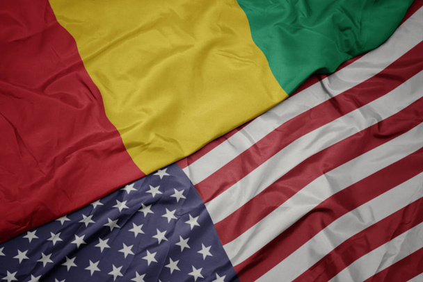 ondeando colorida bandera de Estados Unidos de América y bandera nacional de Guinea
. - Foto, imagen