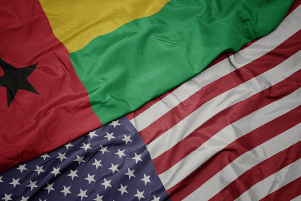 falujące kolorowe flagi Stanów Zjednoczonych Ameryki i flagi narodowej Gwinei Bissau. - Zdjęcie, obraz