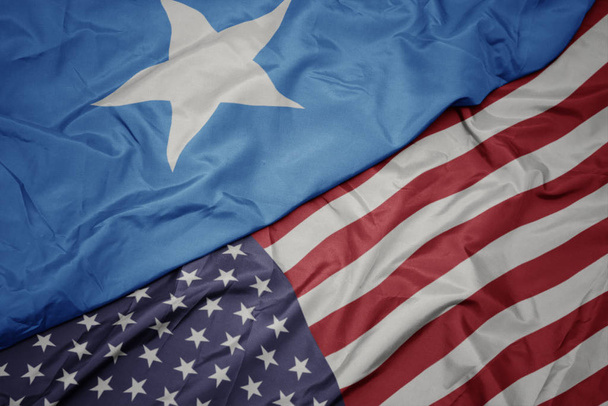 falujące kolorowe flagi Stanów Zjednoczonych Ameryki i flagi narodowej Somalii. - Zdjęcie, obraz