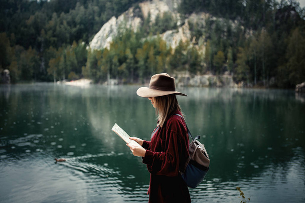 Young woman in hat and red shirt with map near lake - Photo, Image