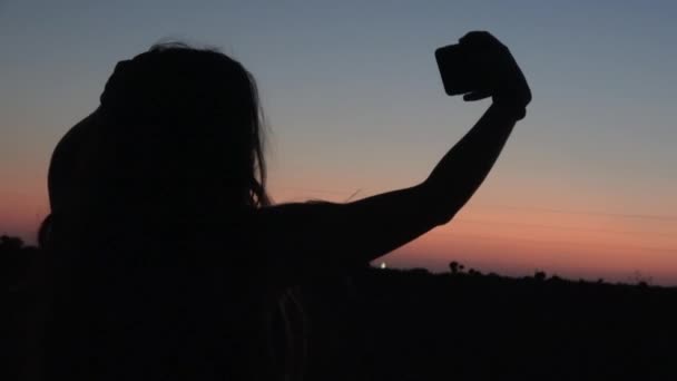 4K. Ultra HD. Silhueta de mulher jovem usando telefone com fundo céu pôr do sol dramático. Sempre conectado, o conceito de tecnologia da Internet
. - Filmagem, Vídeo