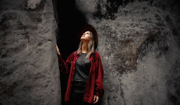 nő kalapban és piros inget a kövek közelében egy hegyekben - Fotó, kép