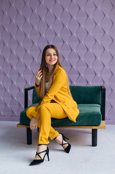 стильна бізнес-леді в жовтому костюмі, що сидить на кріслі і l
 - Фото, зображення