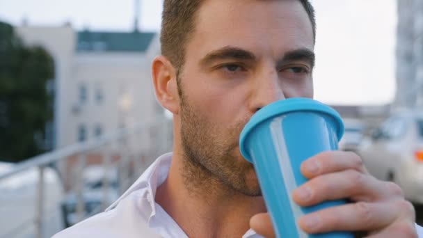 Zbliżenie portret przystojny człowiek picie pyszne kawy w City Urban Lifestyle. Udany pracownik biznesmen patrząc na kamerę. - Materiał filmowy, wideo