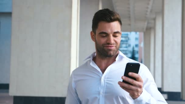 Young Successful Businessman Using Smartphone near Office Building. Bearded Handsome Man Wearing White Shirt. Business Lifestyle. - Felvétel, videó