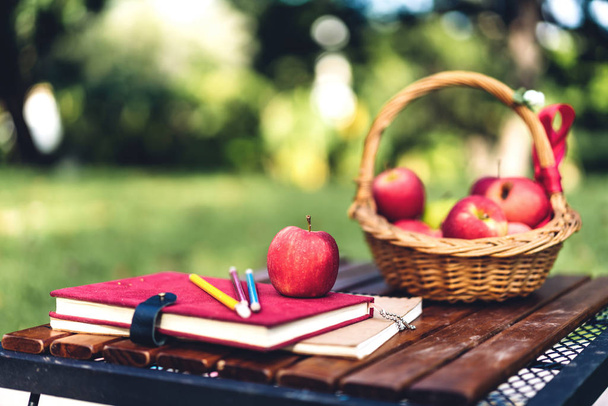 Stacked books and fresh red apple on the table in park.School ac - Photo, Image