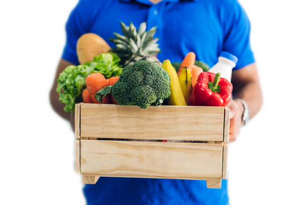 Entrega hombre en uniforme azul que lleva el paquete de comida de comestibles wi
 - Foto, imagen