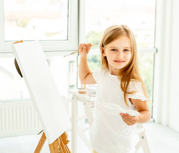 Cute little girl paints on canvas - Zdjęcie, obraz