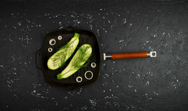 Fresh green zucchini in a pan on a dark table. The view from the top. Copy space. - Valokuva, kuva