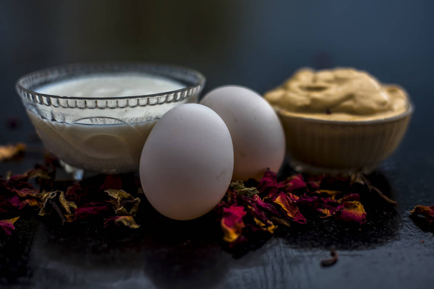 bowls with DIY face mask of multani mitti and yogurt with with eggs on black wooden surface for remedy of even skin  - Fotografie, Obrázek