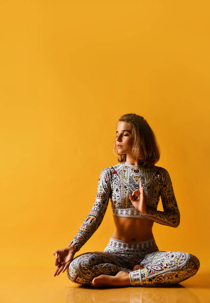 Young attractive woman practicing yoga, working out, wearing sportswear, full length on a yellow background in the studio. Isolated - Foto, Bild
