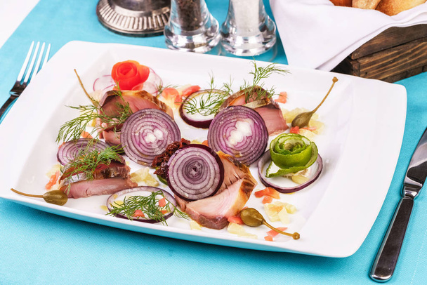 European cuisine, Mediterranean dish. Sliced salted and smoked fish, greens, seasonings and fresh vegetables with onions - Foto, Bild