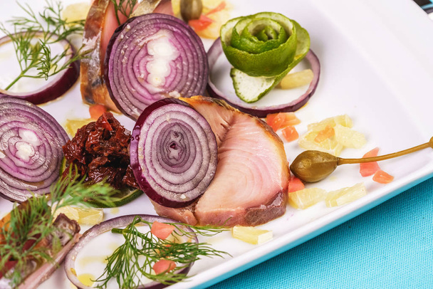 Europäische Küche, mediterranes Gericht. geschnittener gesalzener und geräucherter Fisch, Gemüse, Gewürze und frisches Gemüse mit Zwiebeln - Foto, Bild