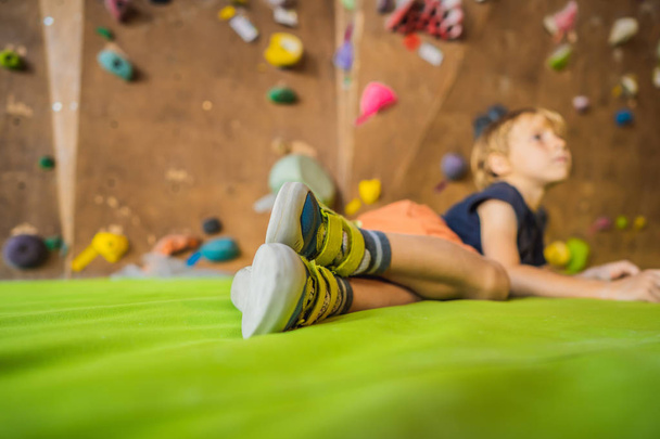 Boy resting after climbing a rock wall indoor - Photo, image