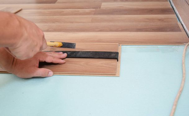Робітник встановлює дерев'яні ламіновані підлоги з інструментами
 - Фото, зображення