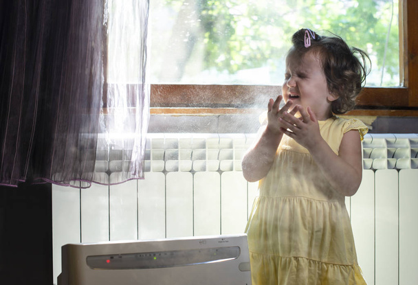 Malá holčička v zaprášené místnosti. Vzduchová čistič a kašlání. Prach - Fotografie, Obrázek