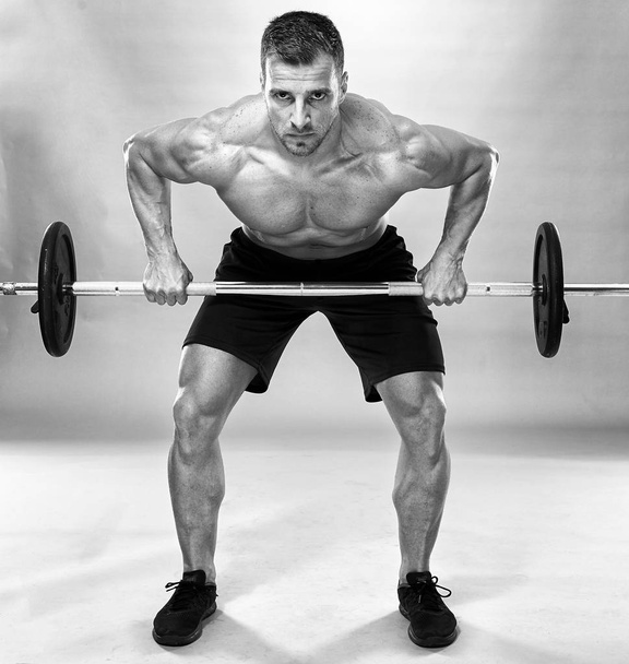Man doing back workout, barbell row in studio over gray background - Photo, Image