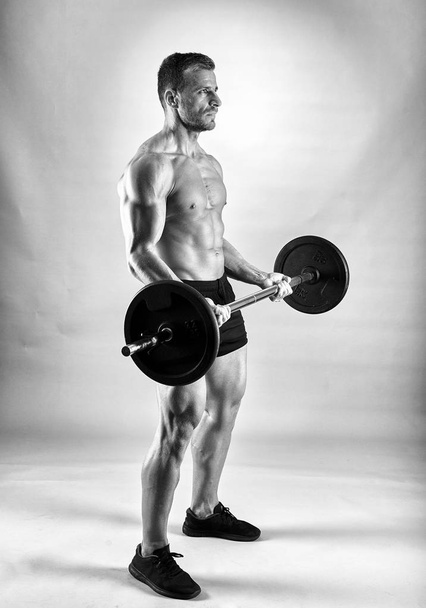 Man doing biceps curl with barbell in studio - 写真・画像